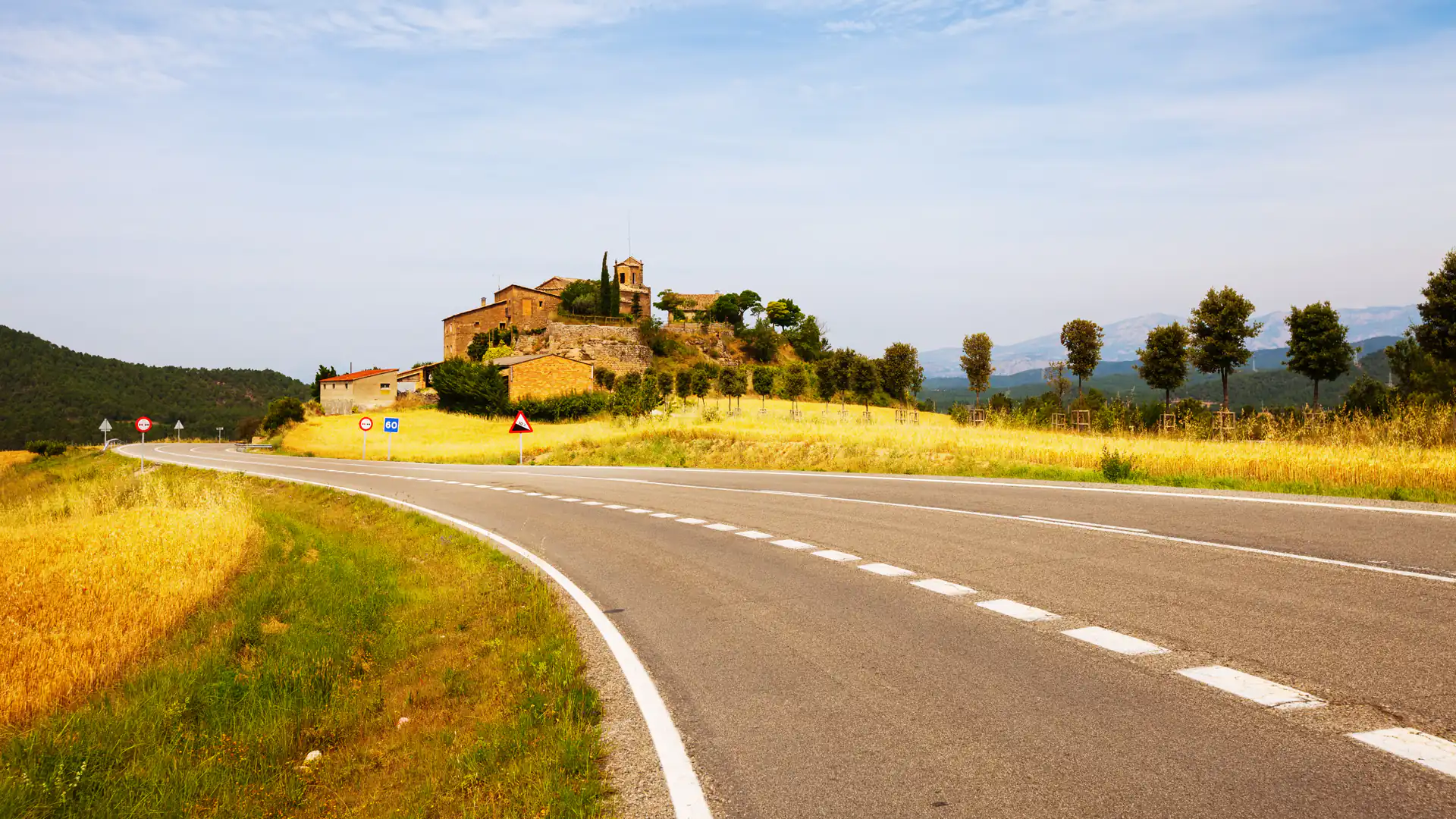 Carretera entre campos con un pueblo al fondo